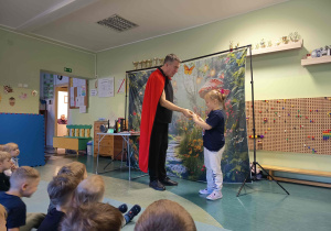 Dziewczynka uczestniczy w pokazie iluzjonisty.