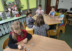 Dzieci oplatają stworzone ludziki folią aluminiową.