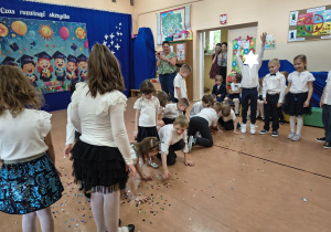 Dzieci bawią sie wystrzelonym confetti na zakończenie programu artystycznego.