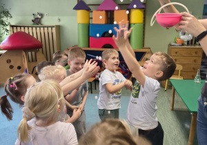 Dzieci próbują łapać bańki wytworzone w reakcji wody z suchym lodem.
