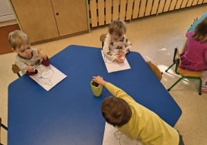 Dzieci kolorują kredkami kropkowe kolorowanki.