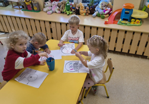 Dzieci kolorują kredkami zabawne kropki.