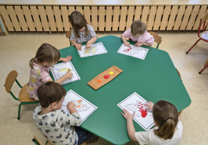 Dzieci wykonują pracę plastyczną z wykorzystaniem farb.