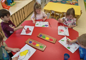 Dzieci malują farbami.