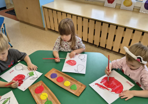 Dzieci malują farbami owoce.