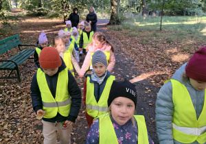 Dzieci spacerują alejkami parku.