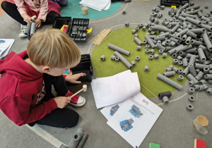 Chłopiec łączy elementy lokomotywy.