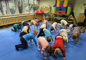 Dzieci wykonują ćwiczenia w pozycji na czworakach.