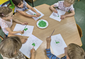 Dzieci nakładają rosnącą farbę na winogrono.