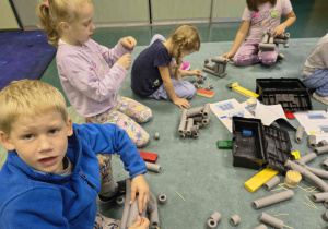 Dzieci wykonują lokomotywę z otulin i wykałaczek.