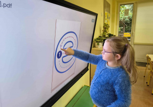 Dziewczynka pisze po śladzie małą literę e.