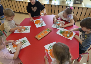 Dzieci malują farbami za pomoca waty umieszczonej w klamerce.