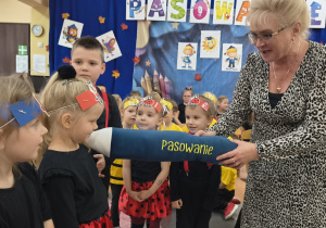Pani Dyrektor pasuje przedszkolaki za pomocą kredki.