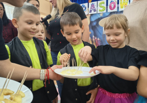 Starszaki biorą z talerzyka cytrynę do zjedzenia.