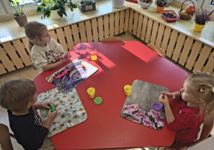 Dzieci zgniatają w rączkach ciastolinę.