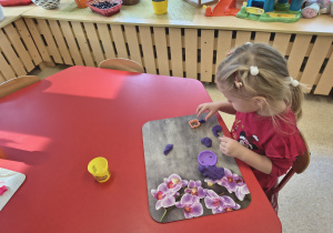 Dziewczynka tworzy kształty z ciastoliny.