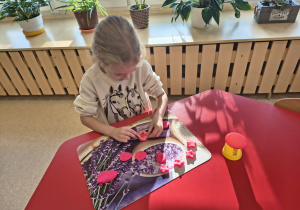 Dziewczynka tworzy ciasteczka z ciastoliny.