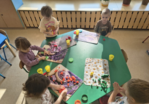 Dzieci usprawniają rączki poprzez zabawę ciastoliną.