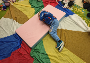 Chłopiec turla się z misiem.