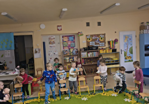 Dzieci uczestniczą w zabawie ruchowej z krzesełkami.