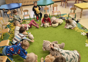 Dzieci kładą się na swoich misiach.