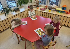 Dzieci przyklejają plastelinę na białych kólkach.