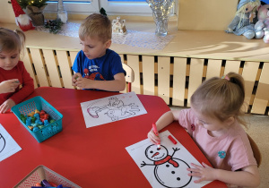 Dzieci kolorują i oglądają świąteczne stempelki.