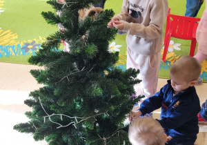 Dzieci ubierają choinkę.