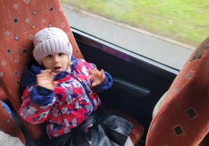 Dziewczynka z grupy Pszczółek siedzi na fotelu w autokarze.