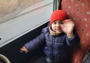 Chłopiec z grupy Pszczółek uśmiecha się i macha do nauczyciela.