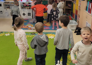 Dzieci obserwują wielką paczkę zostawioną pod choinką przez Świętego Mikołaja.