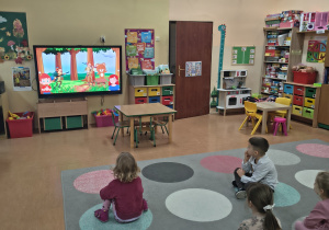 Dzieci oglądają na tablicy interaktywnej historię pluszowego misia.