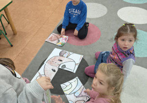 Dzieci układają ogromne puzzle z wizerunkiem misia.