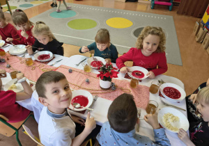 Dzieci jedzą czerwony barszczyk.