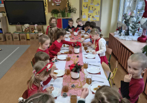 Dzieci jedzą uroczysty obiad przy wspólnym stole.