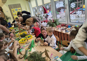 Rodzice wspólnie z dziećmi wykonują choinki.