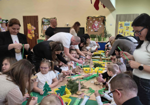 Rodzice wykonują wspólnie z dziećmi choinki.