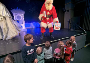 Mikołaj rozdaje prezenty dzieciom.