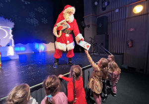 Mikołaj rozdaje dzieciom książki.