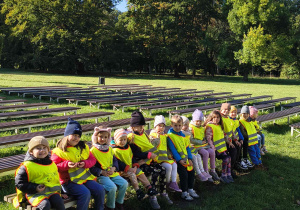 Przedszkolaki siedzą na ławce w parku.