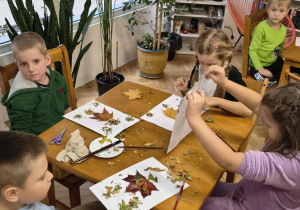 Dzieci wyklejają suknię pani jesieni.