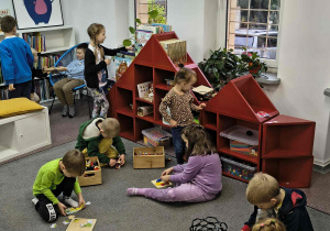 Przedszkolaki bawią się klockami na dywanie.