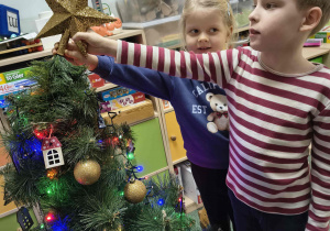Dzieci zawieszają gwiazdę na choince.
