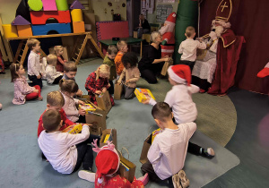 Dzieci oglądają otrzymane od Mikołaja prezenty.