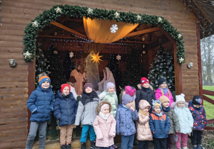 Zdjęcie grupowe dzieci z grupy Biedronek przed szopką.