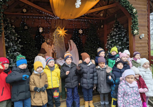 Zdjęcie grupowe dzieci z grupy Motylków przed szopką.