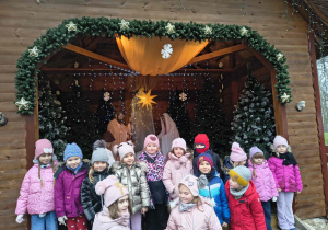 Zdjęcie grupowe dzieci z grupy Sówek przed szopką.