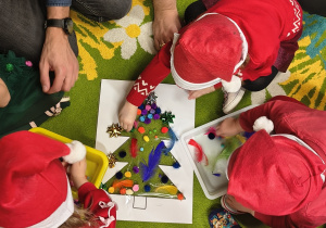 Dzieci ozdabiają choinkę.