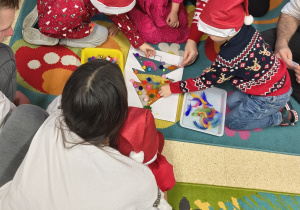 Dzieci ozdabają choinkę z rodzicami.