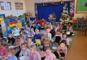 Dzieci jedzą popcorn podczas oglądania bajki.